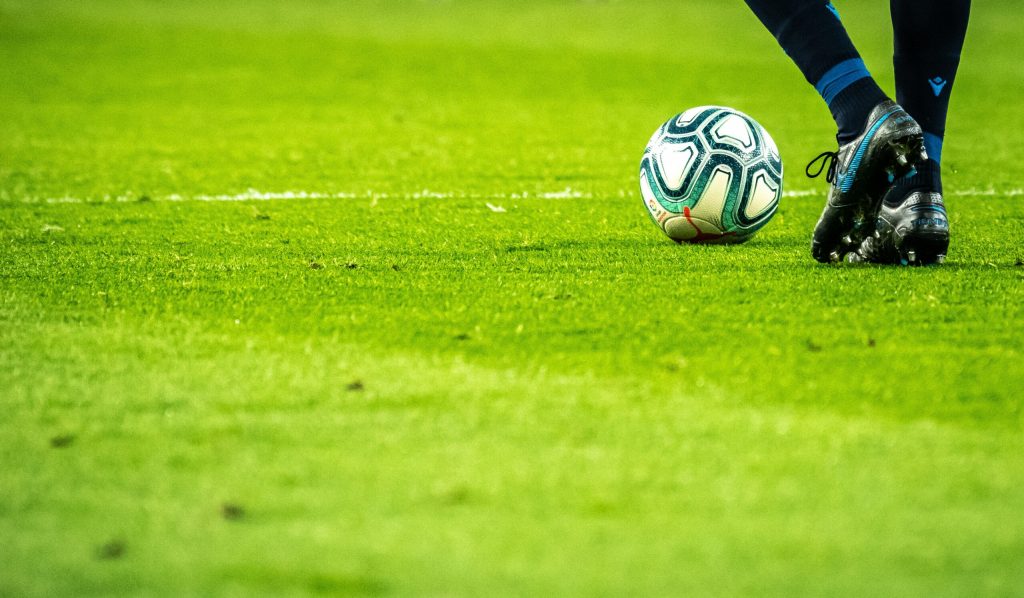 Footballer on pitch during a match, ready to kick the ball.