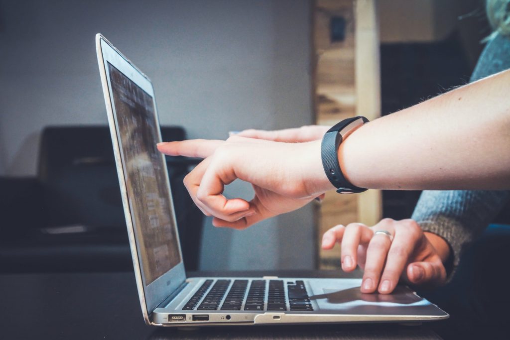 Two men completing a web hosting task on their laptop. 