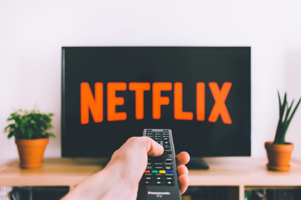 A viewer pressing play on their remote to watch Netflix on their TV. 