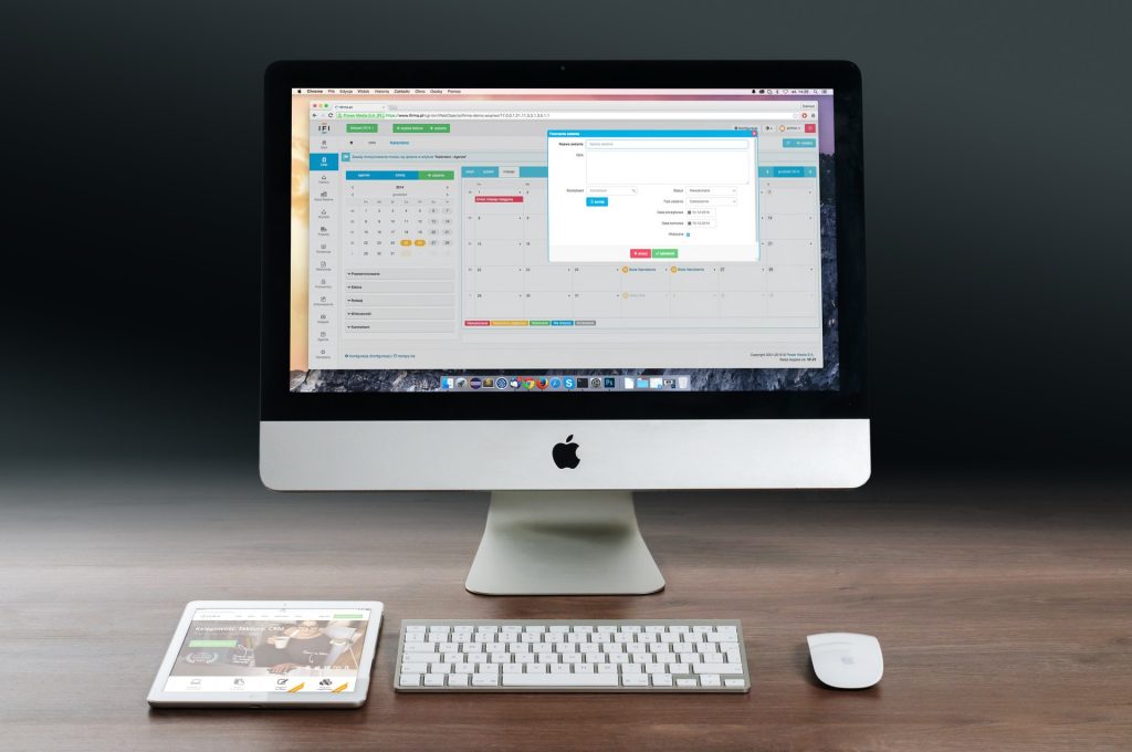 A Mac on a desk displaying a calendar, data, and other information. 