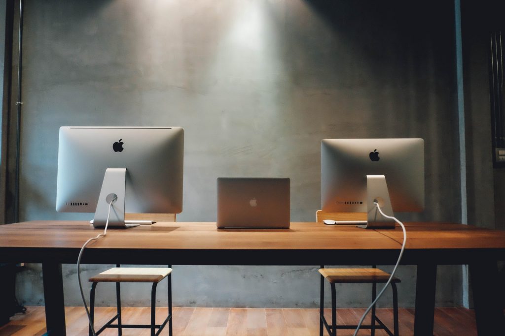 To Mac desktops and a single MacBook on a desk.